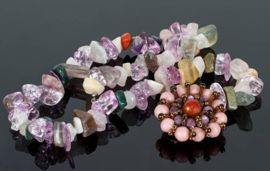 Broş ve ametist, florit, Jasper, Carnelian ve gül kuvars kristallerinin siyah masa üzerinde kaybolması.. 