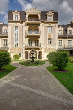 Çeşme ve çalılar yeşillik ile üç-storyed evi