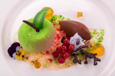 Bir tatlı kırmızı kuş üzümü, çikolata, meyve jöle ve çiçekler ile yeşil elma şeklinde