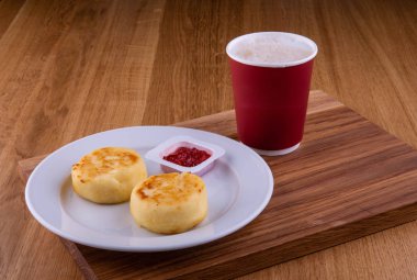 Kiraz reçeli ile cheesecakes bir plaka üzerinde bir fincan kahve ile servis edilir