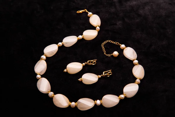 A beige beads and earrings with gold inserts on a chain