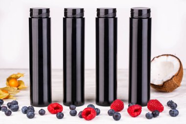 Taze çilek ile beyaz bir arka plan üzerinde siyah parlak şişeler