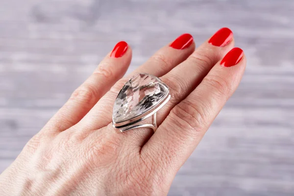 A ring in a silver facet with a stone rhinestone on a hand
