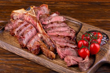 Yumuşak kuzu eti, orta pişmiş, domatesli bir tahtada servis ediliyor.