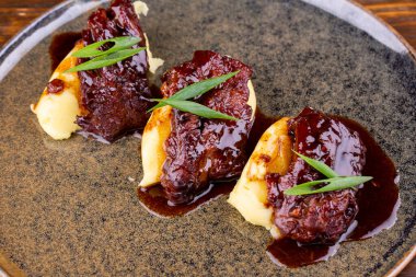 Biftek, erik soslu, patates püresi ile servis edilmiş.