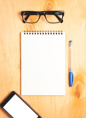 İş gerekli. Ahşap Resepsiyon arka plan üzerinde sarmal boş defter ve smartphone üstten görünüm