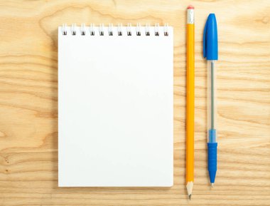 Ahşap Resepsiyon zemin üzerine açık sarmal boş defter kalem ve kurşun kalem ile üstten görünüm