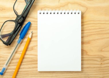 Ahşap Resepsiyon arka plan üzerine açık sarmal boş defter, Gözlük, kalem ve kurşun kalem üstten görünüm