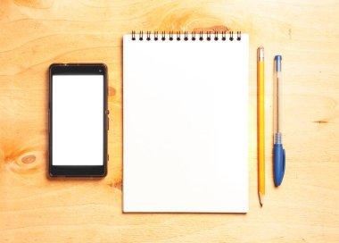 İş gerekli. Ahşap Resepsiyon arka plan üzerinde sarmal boş defter ve smartphone üstten görünüm