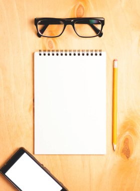 İş gerekli. Ahşap Resepsiyon arka plan üzerinde sarmal boş defter ve smartphone üstten görünüm