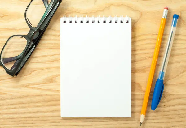 Ahşap Resepsiyon arka plan üzerine açık sarmal boş defter, Gözlük, kalem ve kurşun kalem üstten görünüm