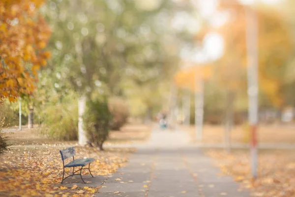 Blurry autumn wallpaper. Old bench in the autumn park. Natural optical tilt shift photo.