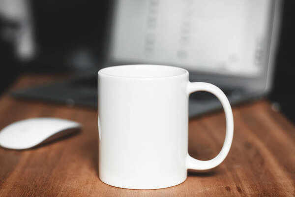 White mug on the wooden table. Office workspace background