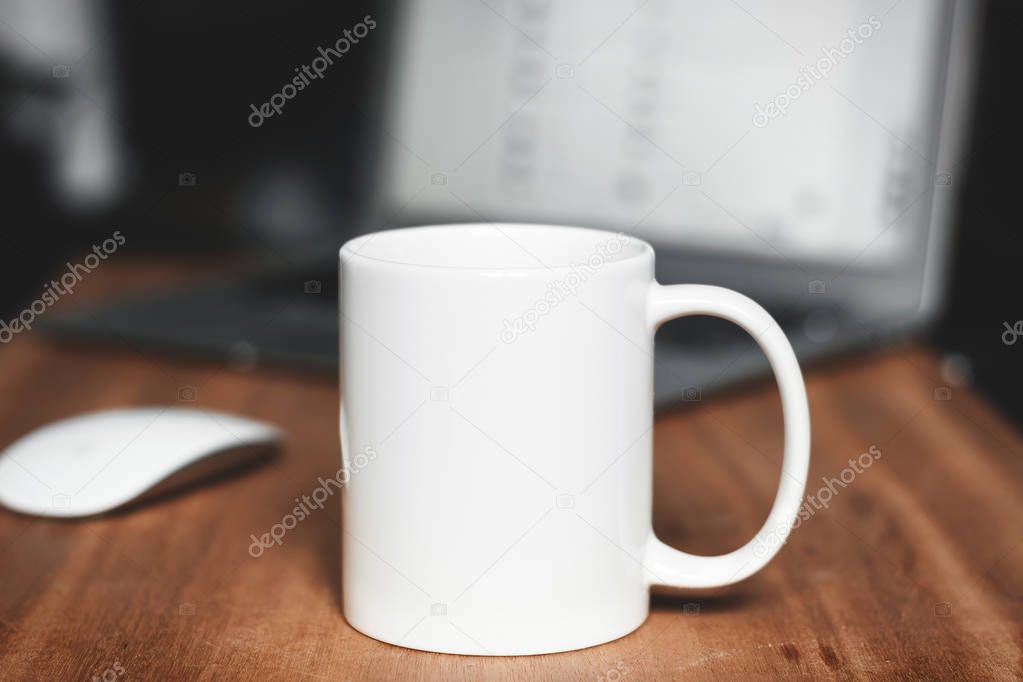White mug on the wooden table. Office workspace background