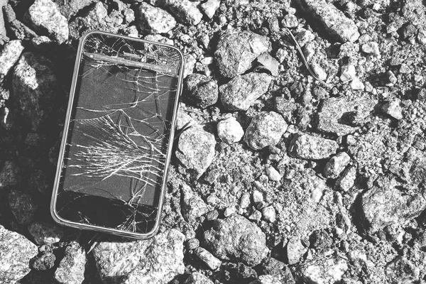 Broken smartphone. Smartphone with broken screen on crushed stone