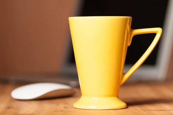 Yellow mug on the wooden table. Office workspace background