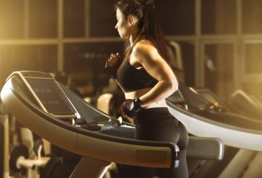 Young attractive woman running on treadmill in fitness center