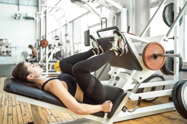 Genç kadınlar bacak ütüleme makinesinde egzersiz yapıyorlar.