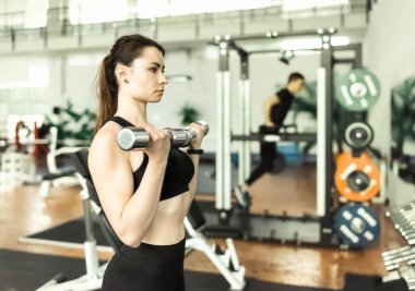 Young athletic women doing exercise with dumbbells