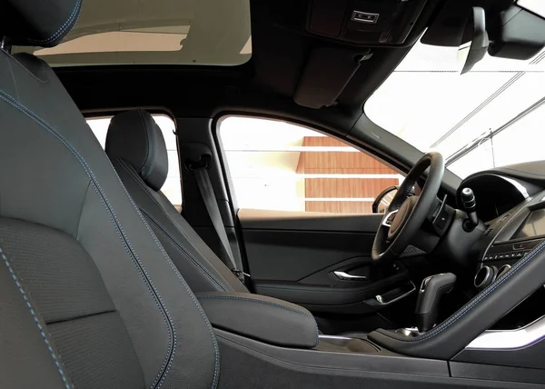 司机和乘客位置在黑皮革与螺纹缝合的车内部的侧面看法 — 图库照片
