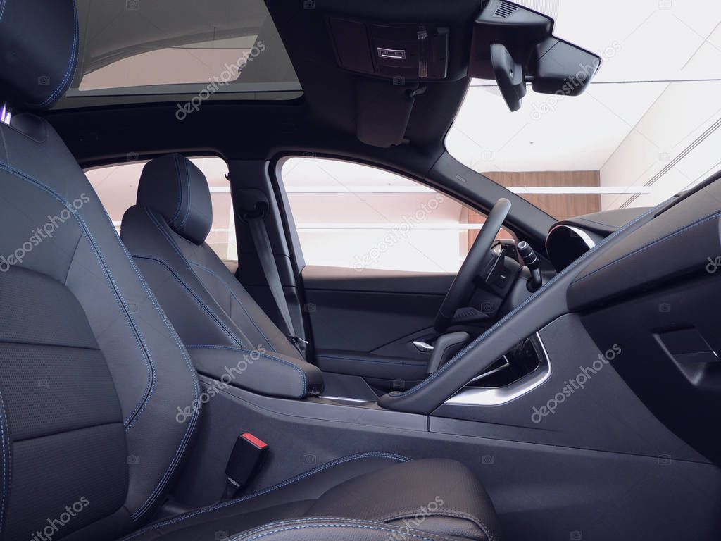 Side view of front leather seats with blue read stitched in car interior 