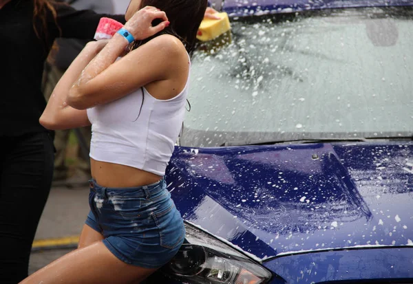 車スポンジ付きぬれた女の子は車を洗う — ストック写真