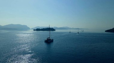 Sabahın erken saatlerinde sakin sularda yüzen yelkenli filosuyla kıyılar arasında güzel bir deniz boğazı. 