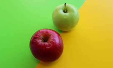 Parlak renkli bir yüzey üzerinde kırmızı ve yeşil elmalar 