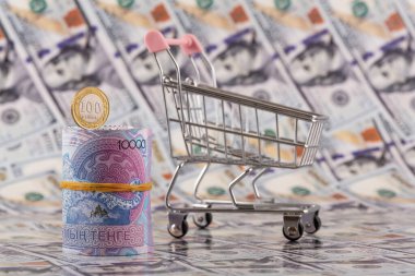 10.000 Kazakistan parası ve 100 onluk madeni para banknotları 100 Amerikan dolarının arka planına karşı.