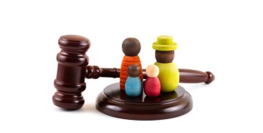 İki çocuklu sembolik bir ailenin tahta figürleri ve beyaz bir arka planda yargıç tokmağı.
