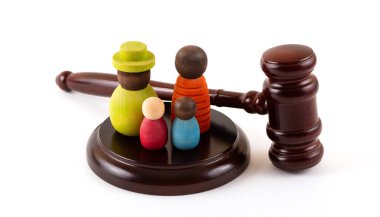 İki çocuklu sembolik bir ailenin tahta figürleri ve beyaz bir arka planda yargıç tokmağı.