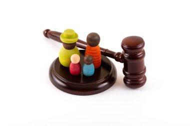 İki çocuklu sembolik bir ailenin tahta figürleri ve beyaz bir arka planda yargıç tokmağı.