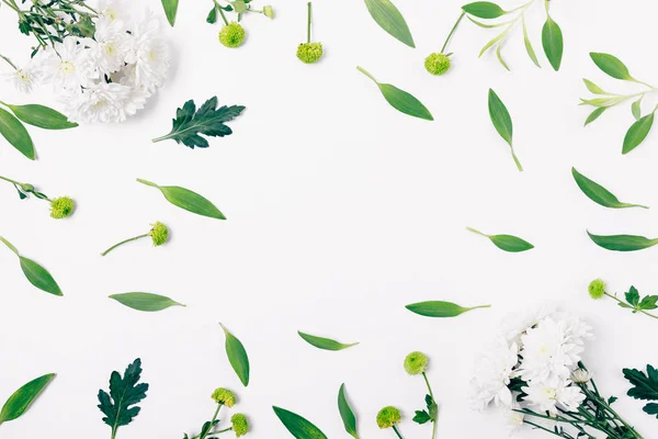 Flat lay composition of fresh flowers and green leaves on white background, top view.