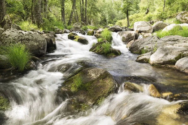 water running down rapids of a river with stones photographed at low speed to give silk effect