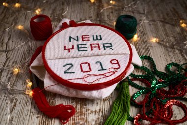 sewing by hand in white taper NEW NEW YEAR 2019 with red and green threads surrounded by party lights clipart