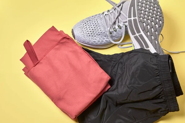 running shoes with a pair of shorts, a red towel and a water bottle on a yellow background