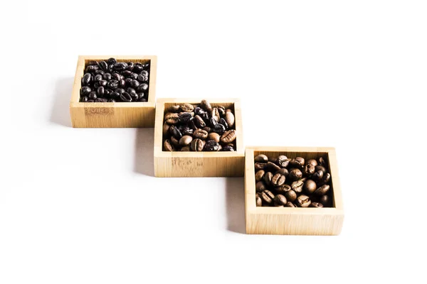 Three groups of different coffee beans in wooden bowls — Stock Photo, Image