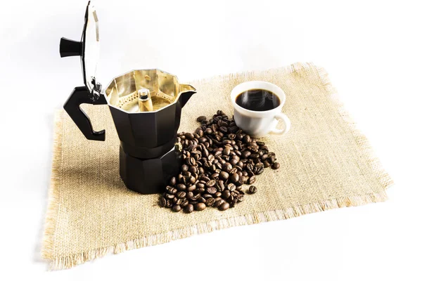 Granos de café junto a una cafetera italiana y una taza con café — Foto de Stock