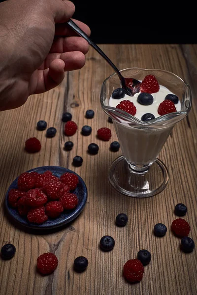 Man eating yogurt with raspberries and blueberries — Stock Photo, Image