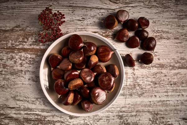 Group of tasty chestnuts next to a bowl — Stock Photo, Image