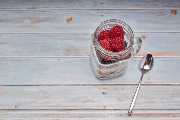 Glass jug filled with cereals, raspberries and blueberries — Stock Photo, Image