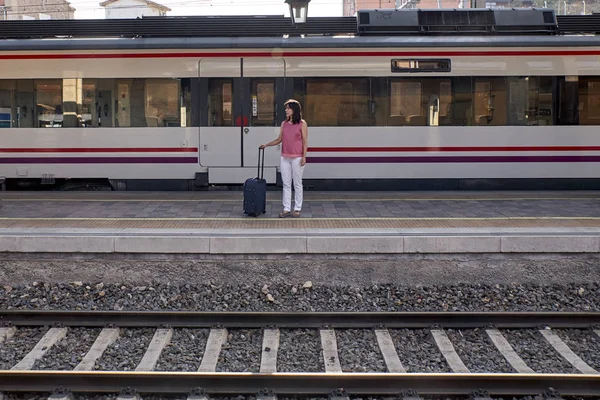 Mulher esperando o trem com uma mala — Fotografia de Stock