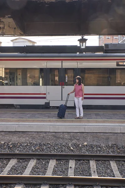 Mulher esperando o trem com uma mala — Fotografia de Stock