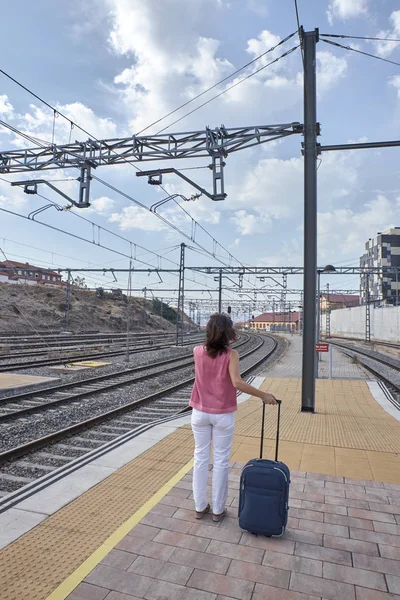 Mulher esperando o trem com uma mala — Fotografia de Stock