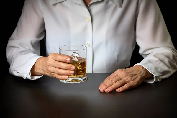 close-up of a woman\'s hands with a glass of Scotch and ice. Concept of social problems