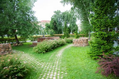 Güzel yaz park çalılar, ağaçlar ve taş ile kaplı yol çiçekler