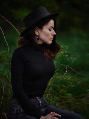 Portre, ormanda siyah şapkalı bir kız.