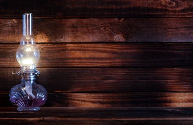 yukarıda ve yan tarafında bir yanan gaz cam ve metal lambası mor üzerinde eski ahşap yüzeye kapalı karanlık karşı ahşap masa yakın görüntü