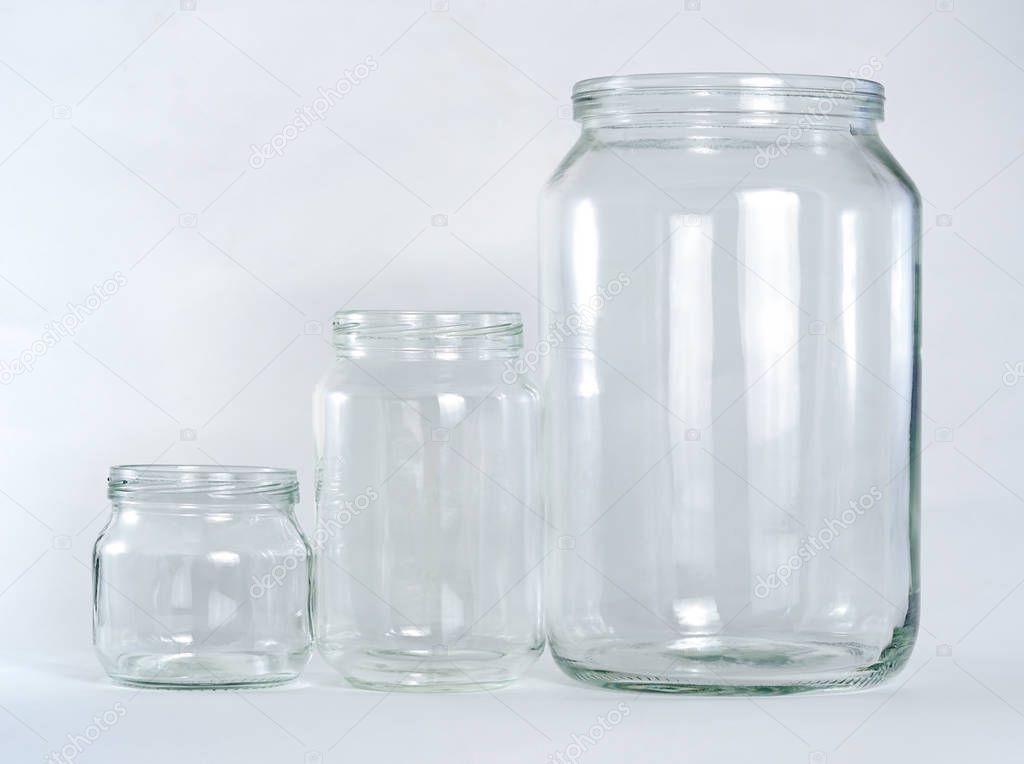 Three empty glass jars of different sizes and volumes are set in a row on a white background.
