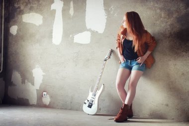 Kızıl saçlı kız bir elektro gitar ile. Rock müzisyen GIR